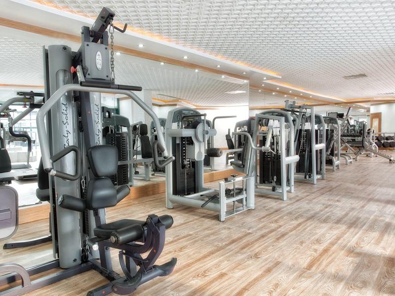 Großer, heller Fitnessraum mit modernen Kraftgeräten und Holzfußboden.