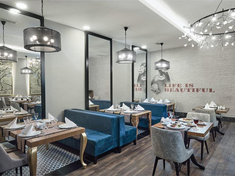 Moderně zařízená restaurace s modrými křesly a stylovými stropními lampami.