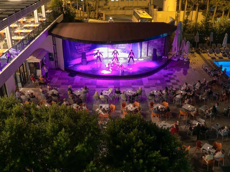 Večerní akce s živou hudbou a publikem vedle osvětleného bazénu v hotelu.