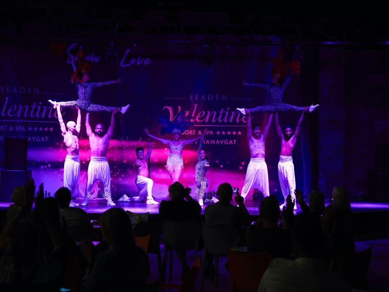 Akrobaté zvedají partnery během představení na pódiu před publikem.