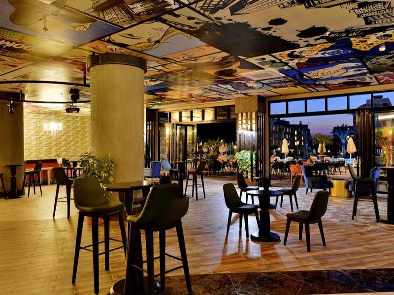 Moderní hotelová lobby s posezením, velkým oknem a barevným dekorovaným stropem