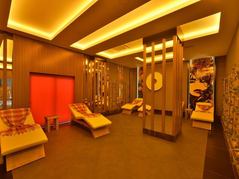 Pohodlná relaxační místnost s lehátky, teplým osvětlením a asijsky inspirovaným dekorem.