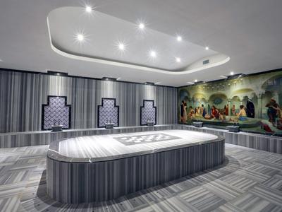 Hammam turco moderno con camas de mármol y un mural colorido en la pared.