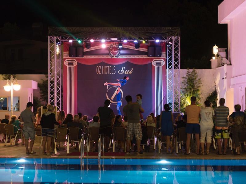 Espectáculo nocturno con malabarista frente a público junto a una piscina iluminada en un hotel.
