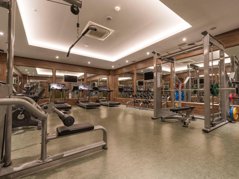 Gimnasio moderno bien equipado con muchas máquinas y espejos grandes.