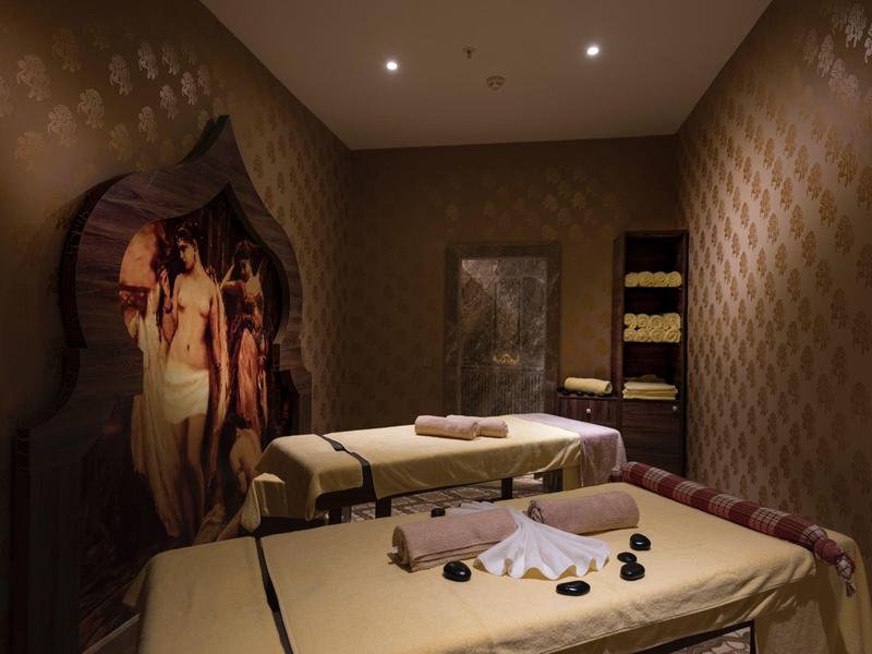 Sala de tratamiento con camillas de masaje, iluminación suave y decoración relajante en un hotel spa.