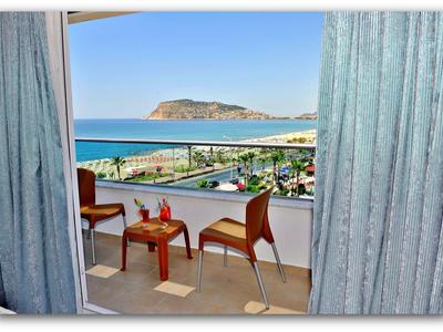 Balcony with two chairs and table, view of sea and island under clear sky