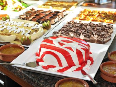 Various cakes and desserts displayed on a buffet table in a hotel restaurant.