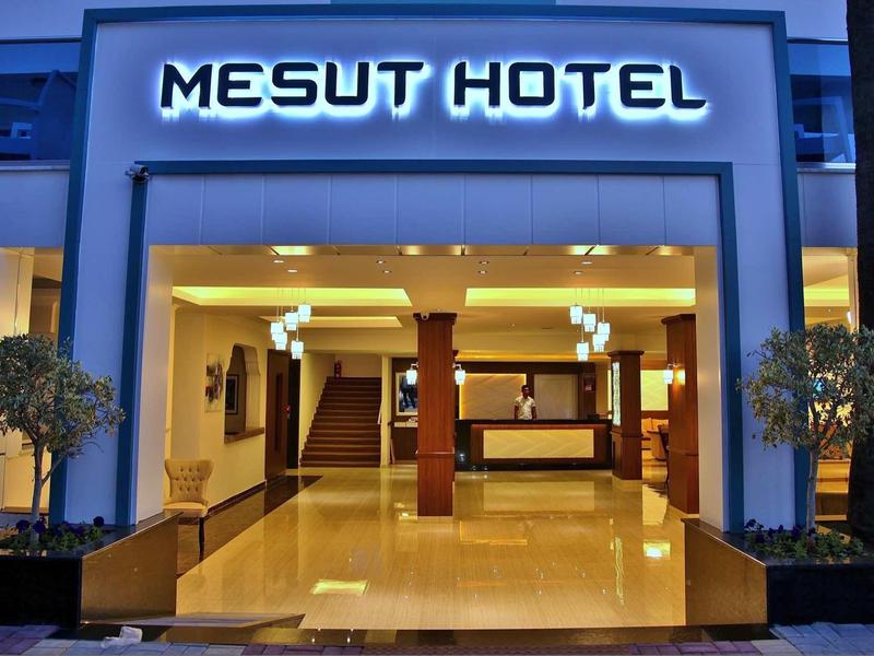 Hotel entrance with illuminated Mesut Hotel sign and reception desk inside.