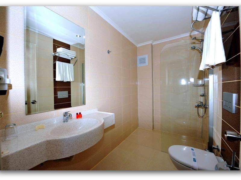 Modern bathroom with large mirror, sink, and shower with glass partition.