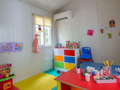 Bunter Kinderraum mit Spielzeug, bunten Regalen, Tisch mit Bastelmaterial und Luftkonditionierer.