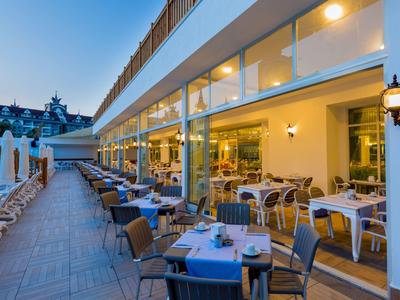 Große Terrasse mit Tischen und Stühlen vor einem modernen Restaurant bei Dämmerung.