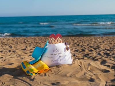 Sabbia della spiaggia con giocattoli di sabbia per bambini e una borsa bianca vicino al mare.