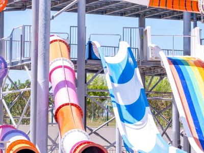 Plusieurs toboggans colorés dans un parc aquatique sous un ciel dégagé.