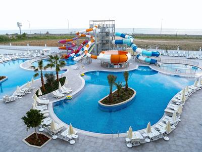 Parc aquatique avec piscine, toboggans et chaises longues en plein air avec vue sur la côte.