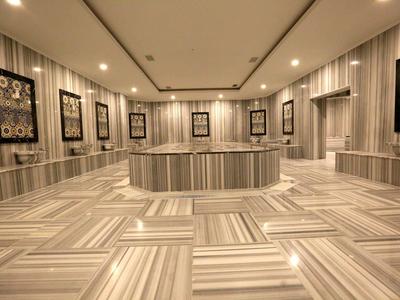 Une salle moderne avec des panneaux muraux rayés, plusieurs cadres et un grand espace central pour s'asseoir.