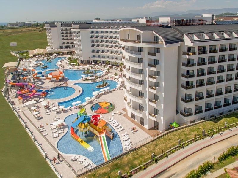 Grand hôtel avec plusieurs piscines et toboggans aquatiques au bord d'une rivière.