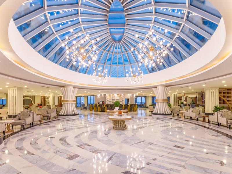 Hall d'hôtel luxueux avec un grand dôme en verre et un sol en marbre brillant.