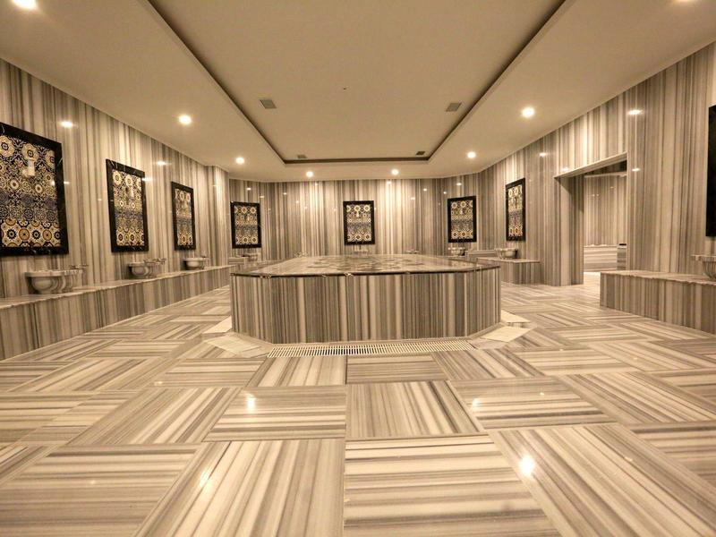 Une salle moderne avec des panneaux muraux rayés, plusieurs cadres et un grand espace central pour s'asseoir.