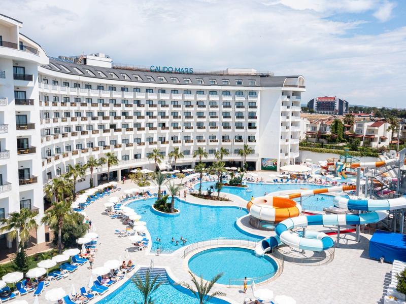 Grand hôtel avec piscine courbe, parasols et vue sur la ville.