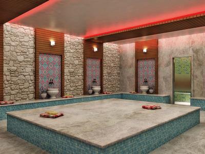 Area spa interna con pareti in pietra, luce calda e vasca centrale in pietra.