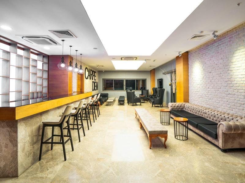 Area lounge moderna dell'hotel con bar, sgabelli e comodi posti a sedere.