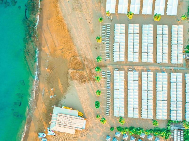Vista aerea di un campeggio sul mare con tende allineate e una spiaggia.