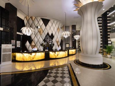 Elegante Hotellobby mit beleuchtetem Empfangstresen, geometrischem Wandmuster und großen Säulen.