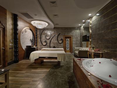Luxuriöses Schlafzimmer mit Holzfußboden, großem Bett, Rundspiegel und Whirlpool in elegantem Ambiente.