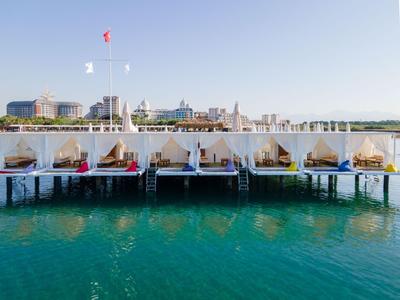 Bungalós de playa de lujo con cortinas blancas sobre agua turquesa bajo un cielo despejado.