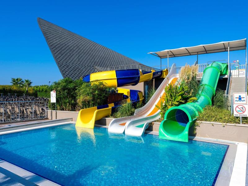 Barevné skluzavky do bazénu pod modrou oblohou v aquaparku.