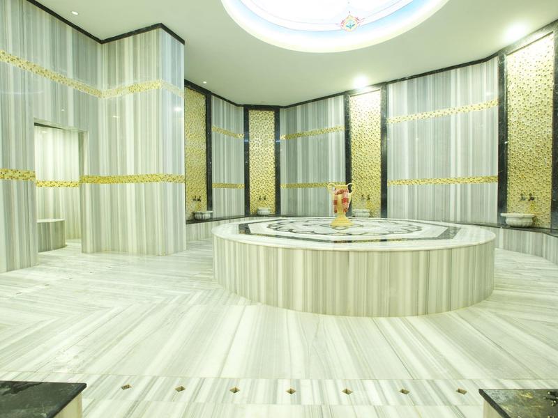 Gran hamam moderno con suelo y paredes de mármol y una fuente central de mármol calentada.