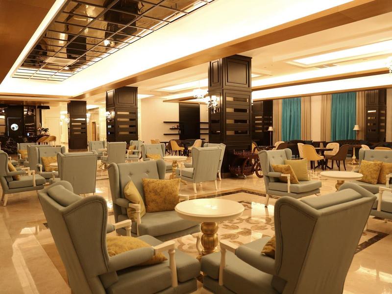 Área de salón acogedora en hotel con sillas y mesas bajo luz cálida.