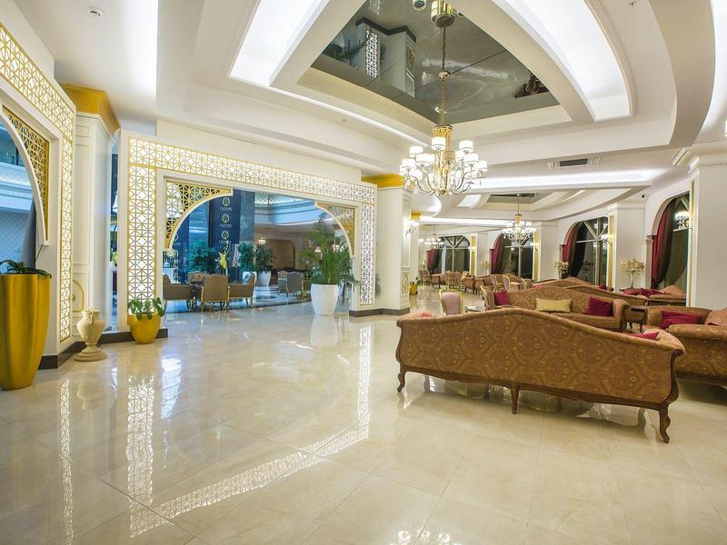 Amplia zona de vestíbulo de hotel con cómodos sofás, candelabros y suelo de mármol.