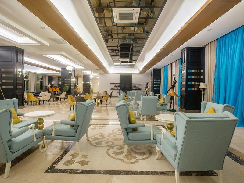 Área lounge moderna de hotel con sillones azules, alfombras y luz clara en el techo.