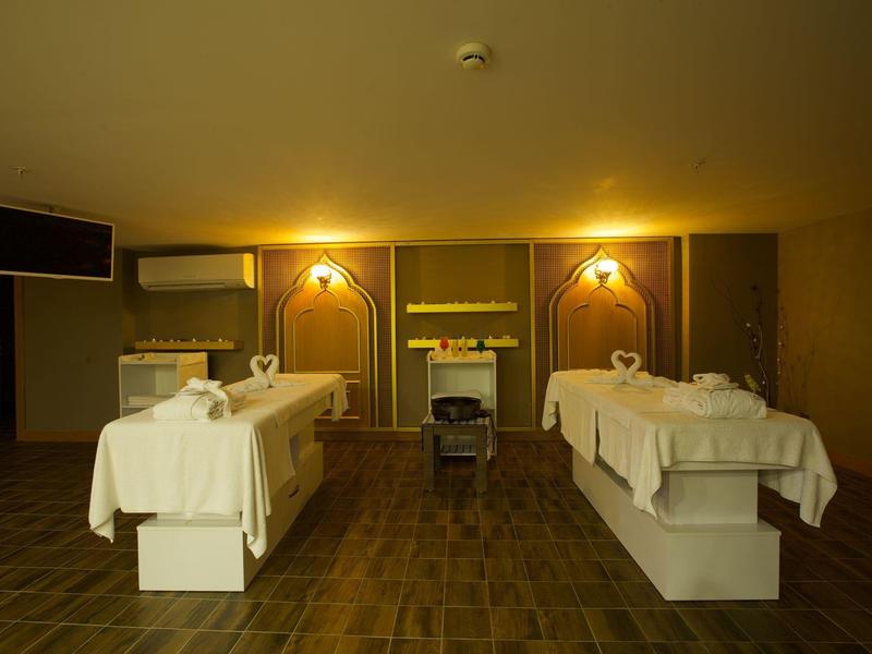 Sala de spa tranquila con dos camillas blancas, luz cálida y diseño minimalista.