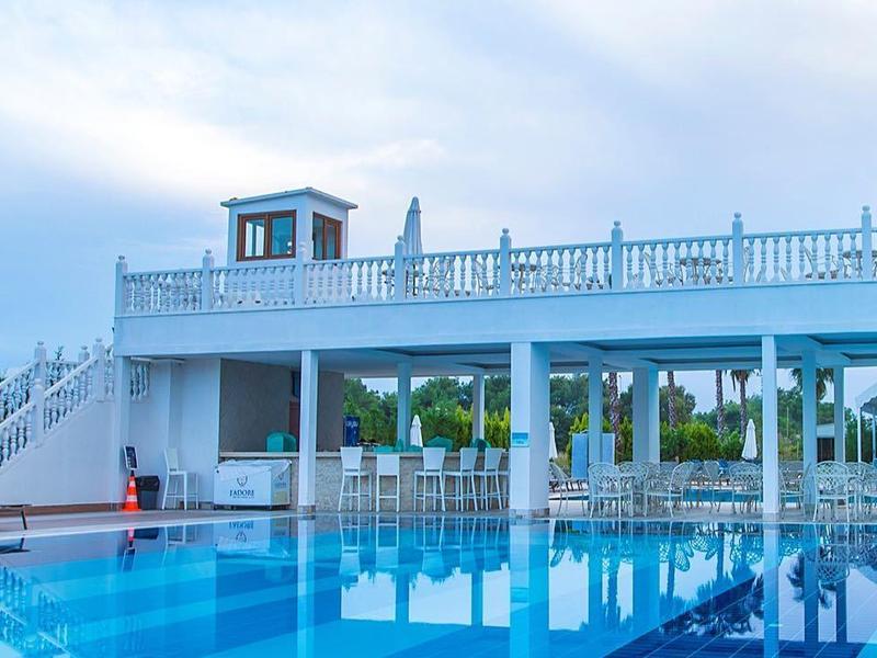 Piscina grande y moderna junto a edificio blanco bajo cielo nublado, ambiente relajante