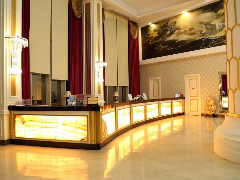 Recepción elegante de hotel con suelos de mármol claros y acentos dorados.