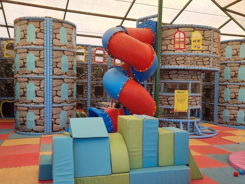 Área de juegos interior colorida con toboganes y bloques suaves en un hotel o resort vacacional.