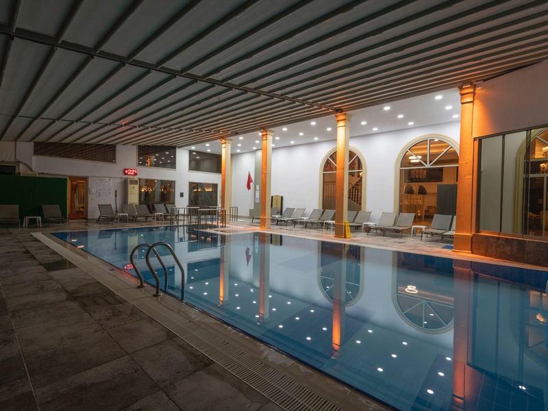 Piscina cubierta climatizada con tumbonas y luz cálida en un entorno hotelero.