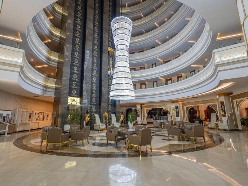 Amplio vestíbulo de hotel con diseño redondo, áreas de descanso y una lámpara principal llamativa.