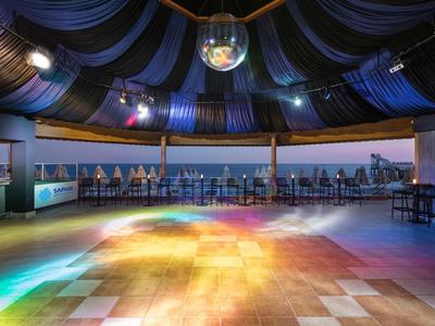 Empty dance floor in a bar with disco ball and colored lights under a tent roof