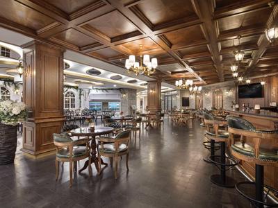 Elegant hotel bar with wooden furniture, chandeliers, and cozy atmosphere.