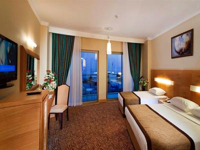 Cozy hotel room with two single beds, TV, and balcony overlooking the night.