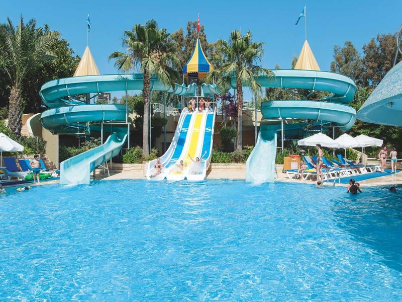 Large swimming pool with water slides and sun umbrellas in a tropical resort.