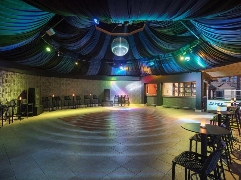 Empty, atmospheric dance hall with disco ball and stage area.