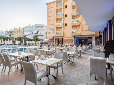 Outdoor dining area with tables and chairs beside a pool in a hotel courtyard at sunset.
