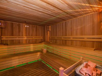 Cozy wooden sauna with tiered benches and warm lighting, featuring a heater with stones.