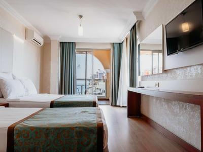 Modernes Hotelzimmer mit zwei Betten, Fernsehgerät und Balkon mit Blick auf die Stadt.