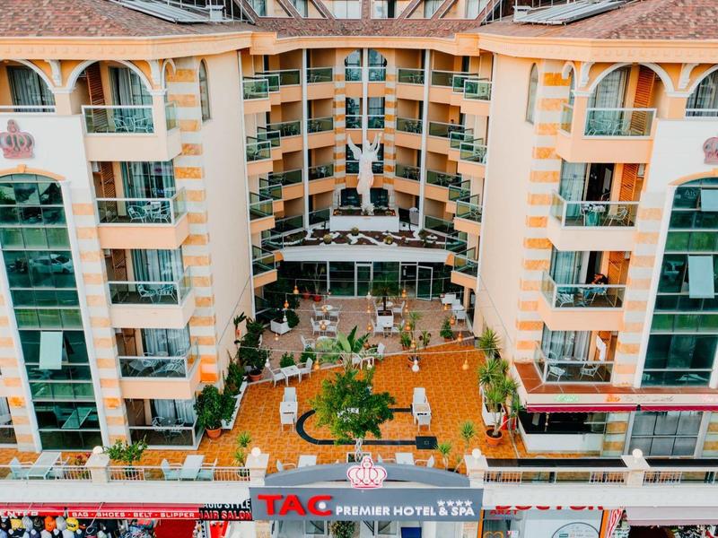 A large hotel with a courtyard featuring seating and greenery, viewed from above.